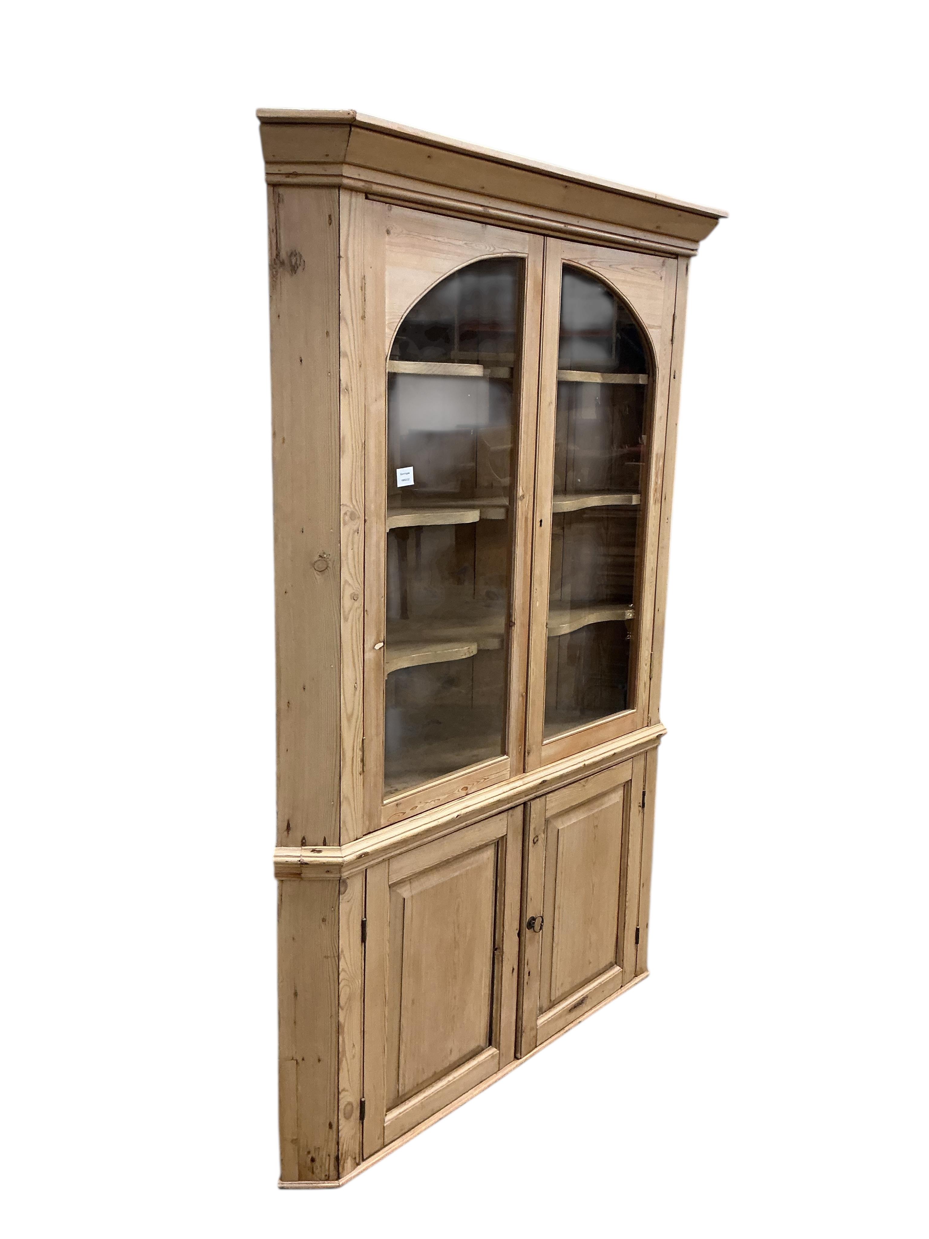 An early 19th century glazed pine standing corner cupboard, width 126cm, depth 62cm, height 191cm